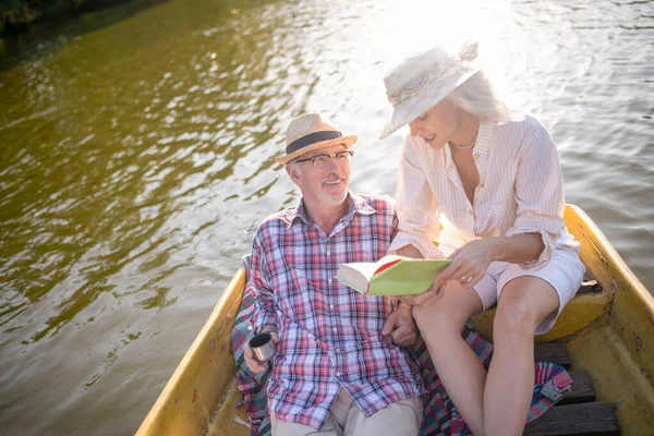 Жена читает книгу для мужа во время поездки на лодке — стоковое фото