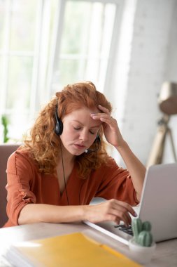 Bilgisayarın önünde oturan serbest çalışan biri, şiddetli bir baş ağrısı çekiyor.