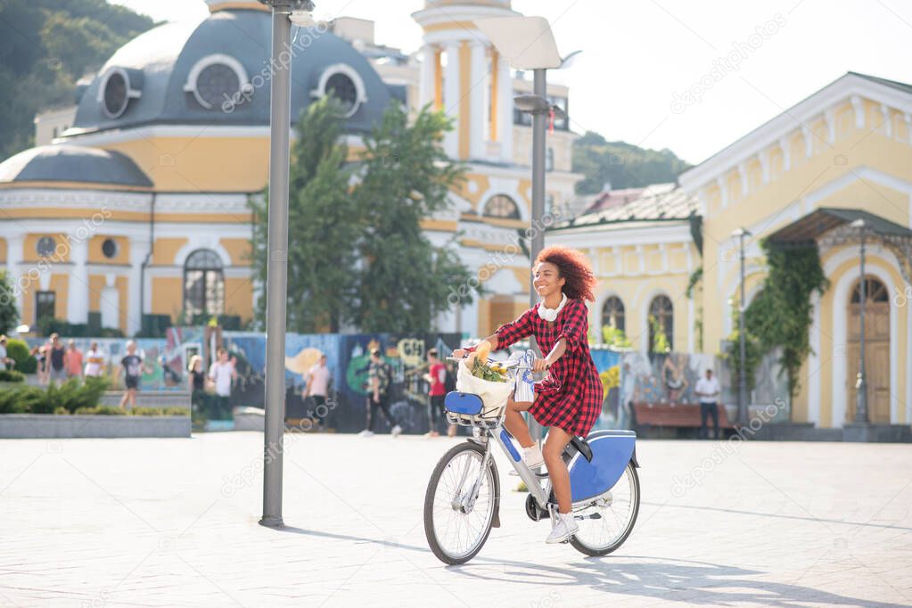 Curly red-haired student riding bike on warm sunny day