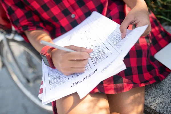 Student wearing red checked shirt writing answers for test — Stock Photo, Image