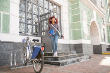 Teslimat ofisinden ayrılıyorum. Şen şakrak kulaklık takan öğrenci teslimat ofisinden klasörle çıkıyor.