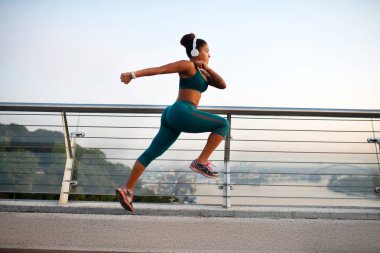 Koyu tenli, beyaz kulaklıklı, hızlı koşan bir kadın.