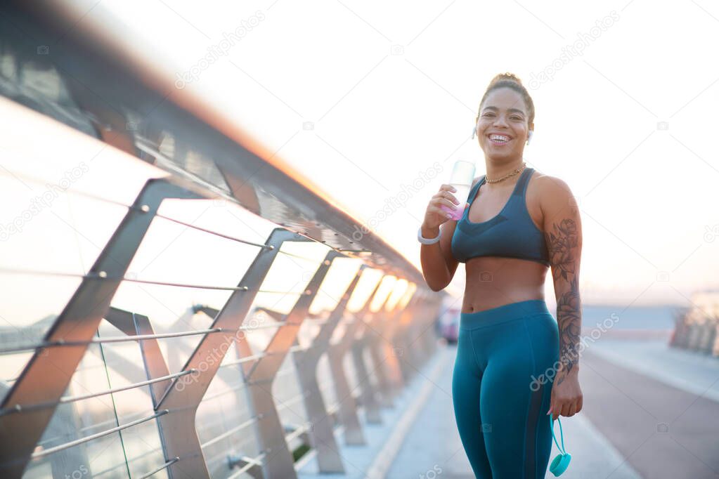 Woman laughing after running in the morning while drinking water