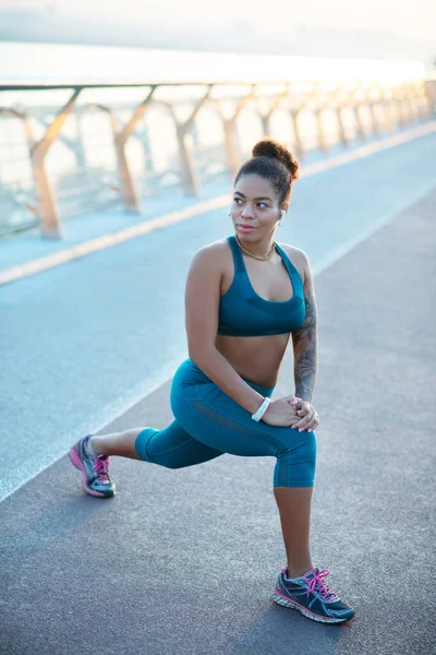 Mulher de pele escura usando leggings e alongamento superior após corrida — Fotografia de Stock