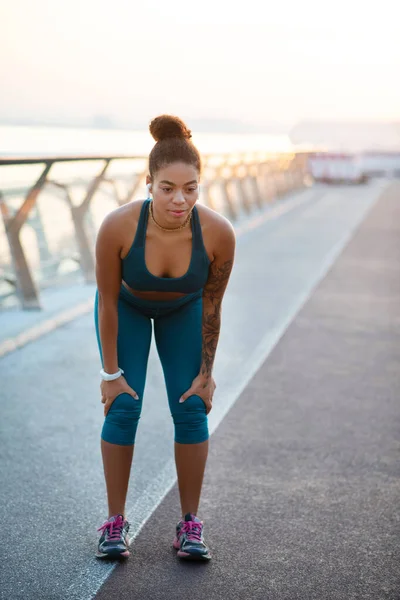 Mujer de piel oscura que usa polainas sintiéndose agotada después de correr — Foto de Stock