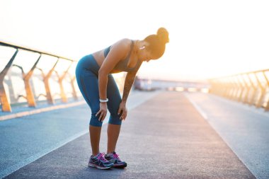 Koyu renk saçlı, kulaklık takan, yavaş nefes alan genç bir kadın.