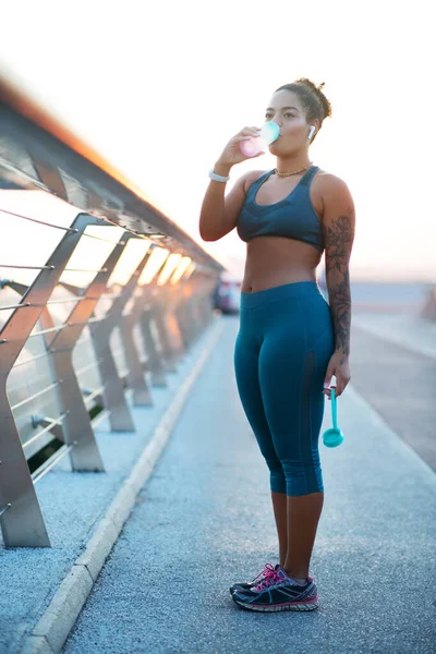 Žena pitná voda po běhu na mostě — Stock fotografie