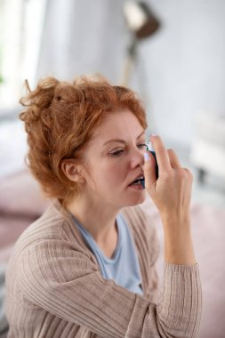 Astım krizi geçiren genç bir kadın. Bu yüzden astım ilacı kullanıyor.