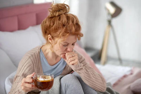Kızıl saçlı kadın sıcak çay içerken öksürüyor. — Stok fotoğraf