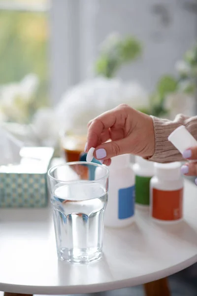 Mulher colocando pílula em vidro de água enquanto toma vitaminas — Fotografia de Stock