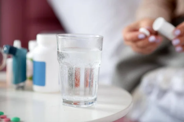 Close up of pill dissolving in glass of water standing on table — Stock Photo, Image