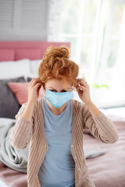 Žena v béžovém svetru nasazením ochranné masky — Stock fotografie