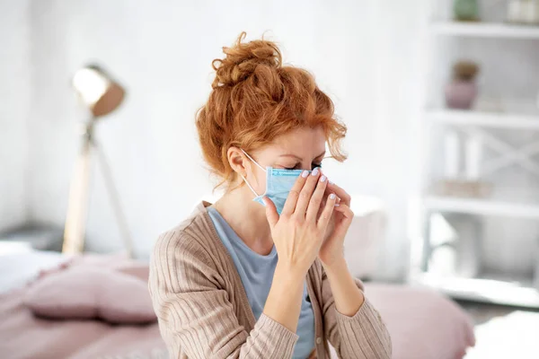 Mujer rizada estornudando después de ponerse una máscara protectora — Foto de Stock