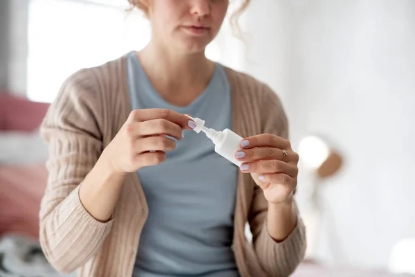 Giovane donna che utilizza spray nasale mentre soffre di freddo — Foto Stock