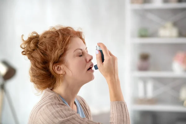 Női tüsszentés az inhalátor használata közben asztma miatt — Stock Fotó