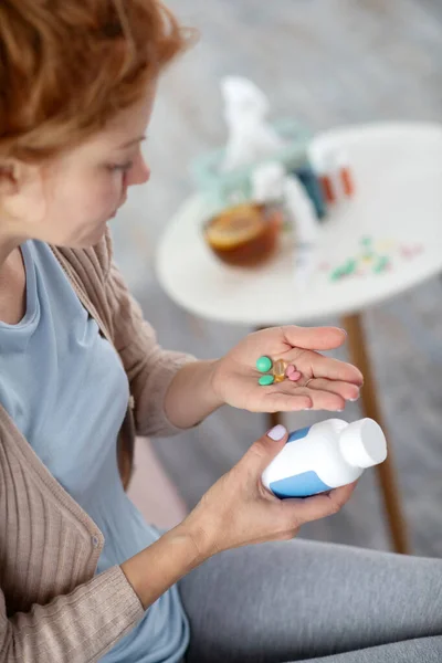 Donna malata che soffre di influenza che tiene pillole sul palmo della mano — Foto Stock