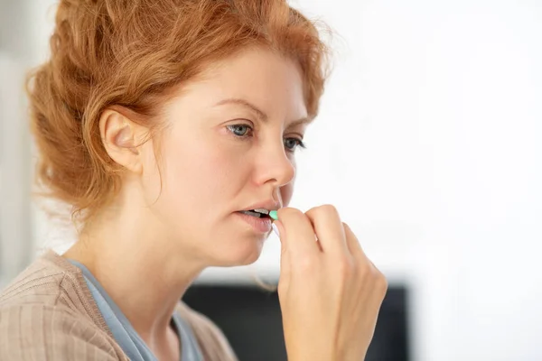 Young blue-eyed woman taking pill while suffering from fever — Stock Photo, Image