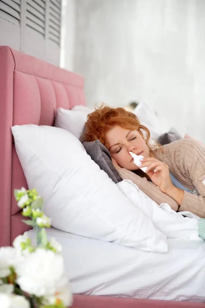 Sleepy sick woman using nasal spray while having stuffy nose — Stock Photo, Image