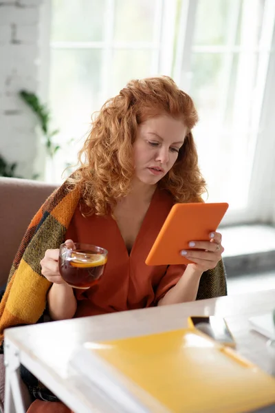 Кучерява жінка тримає планшет під час читання новин в Інтернеті — стокове фото