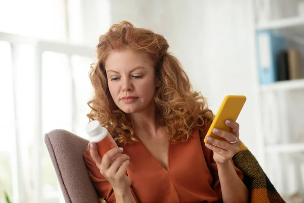 Mujer rizada sosteniendo teléfono inteligente amarillo después de enviar mensajes de texto médico — Foto de Stock
