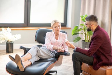 Kadın rahat koltukta oturup doktorların tavsiyelerini dinliyor.