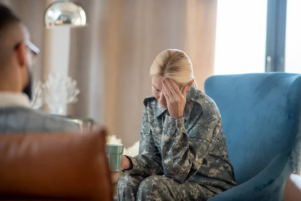 ストレスの多い出来事を思い出しながら頭痛を持つブロンド軍の女性 — ストック写真