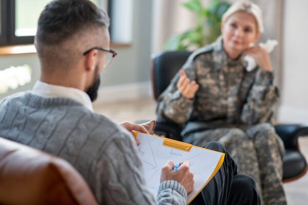Psychologist making notes and writing during military rehabilitation