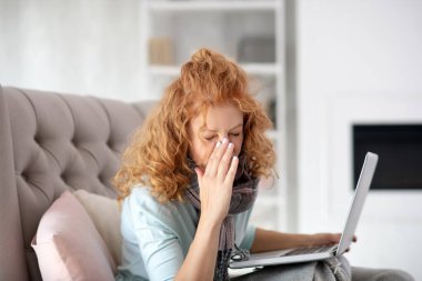 Kızıl saçlı kıvırcık kadın film izlerken hapşırıyor.