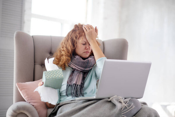 Curly woman holding pack of napkins while having stuffy nose