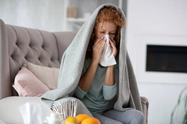 Red-haired woman using napkin while having stuff nose — Stock Photo, Image