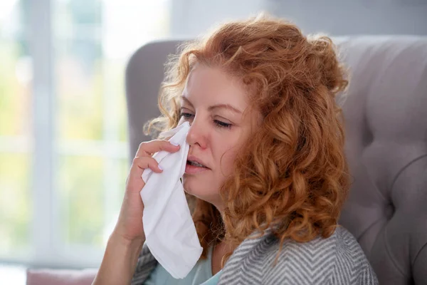 Vrouw die servet vasthoudt terwijl ze niest en zich duizelig voelt — Stockfoto