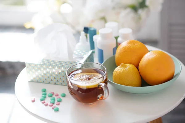 Чашка чая с лимоном рядом с тарелкой с апельсинами и витаминами — стоковое фото