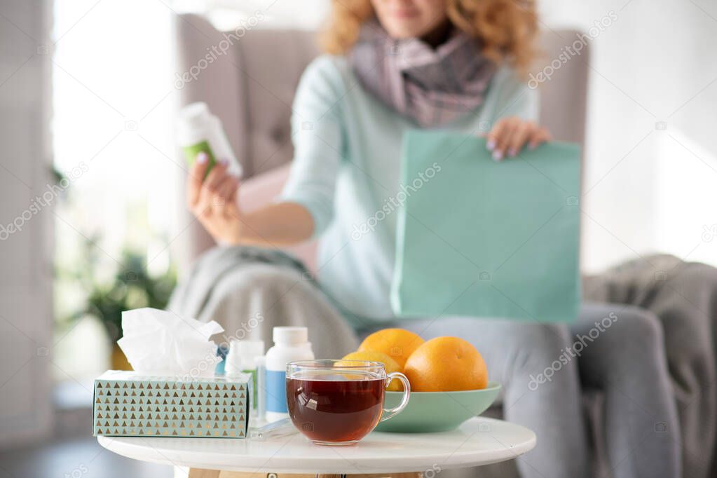 Orange and tea standing on the table while woman having flu