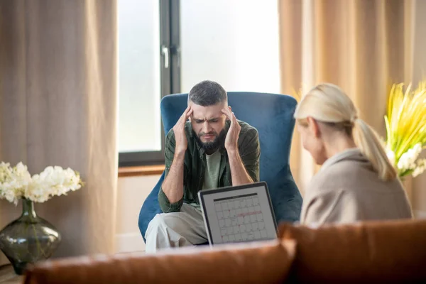 Hombre con dolor de cabeza mientras habla con psicólogo —  Fotos de Stock