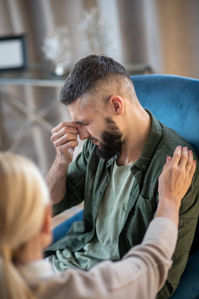 Psychoanalyst supporting man having strong headache during talk