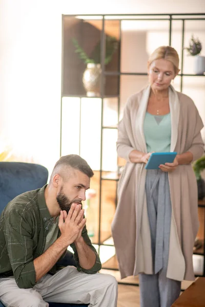 Blond psykoanalytiker håller tabletten stående nära mannen — Stockfoto