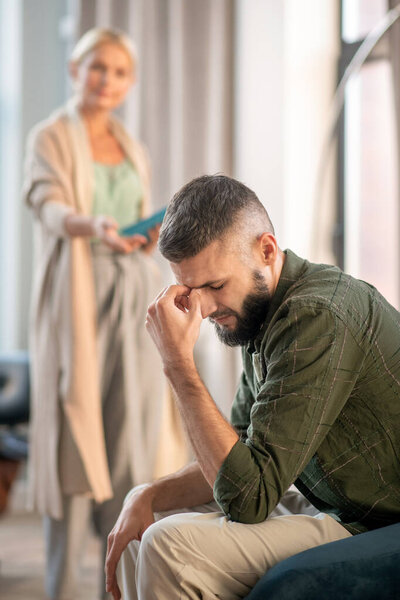 Bearded man feeling upset while speaking with psychoanalyst