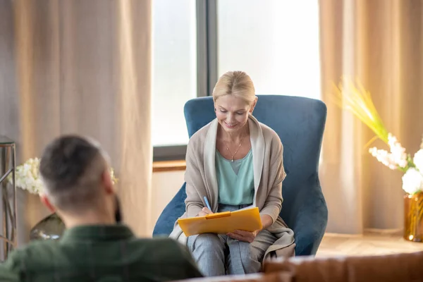 Psykoanalytiker ler när de antecknar och pratar med patienten — Stockfoto