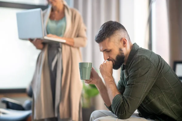 Bearded man drinking tea and speaking with psychoanalyst — Stock Photo, Image