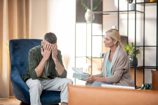 Dark-haired man having tears while reminding stressful moments