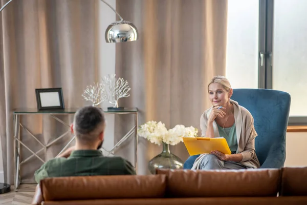 Rubia psicoanalista hablando con paciente en espaciosa y acogedora habitación — Foto de Stock