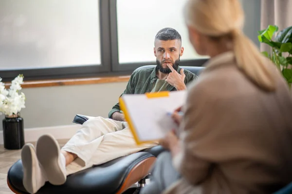 Mannen sitter på bekväm fåtölj och delar med sig av sina tankar — Stockfoto