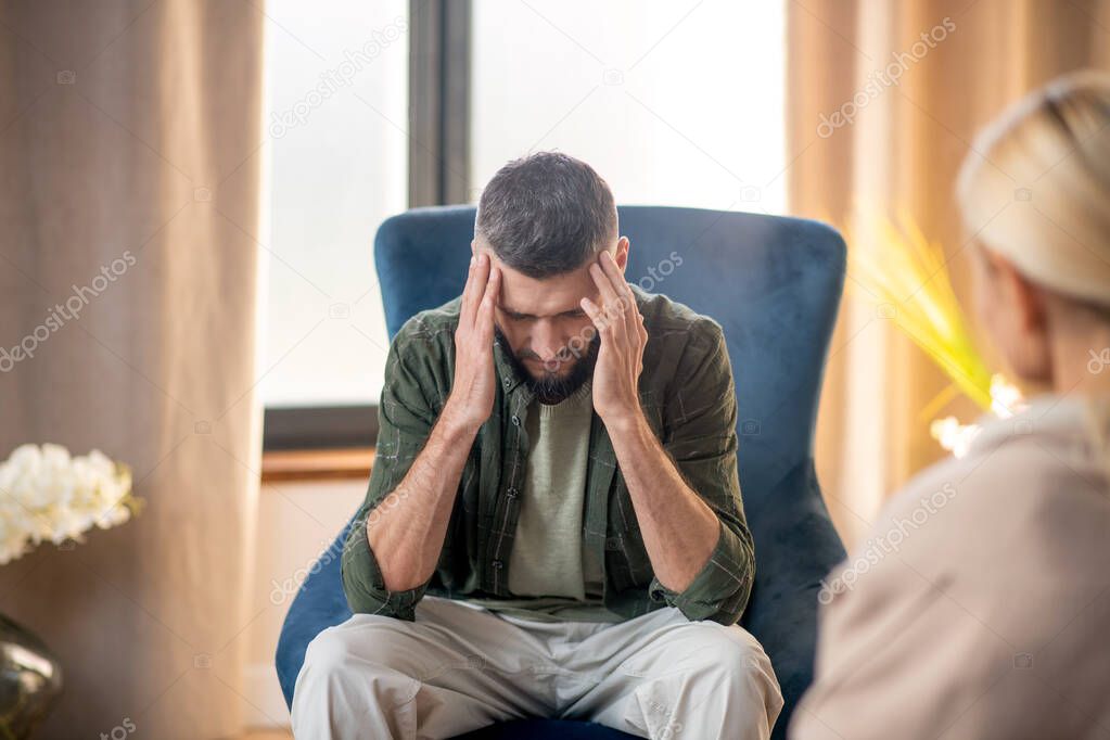 Man suffering from headache while having psychoanalysis