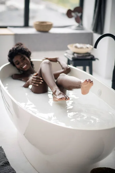 Strahlende Frau zeigt ihr zahmes Lächeln beim Chillen in der Badewanne — Stockfoto