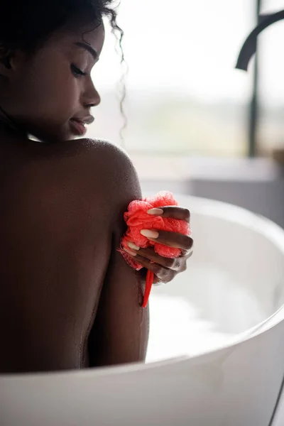 Close up of dark-skinned woman holding pink loofah — ストック写真