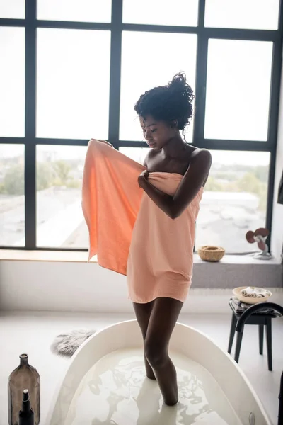 Frau trocknet Körper mit Handtuch aus, das am Fenster steht — Stockfoto