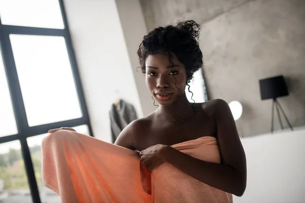 Кудрявая темноглазый женщина покрывает тело в полотенце после принятия ванны — стоковое фото