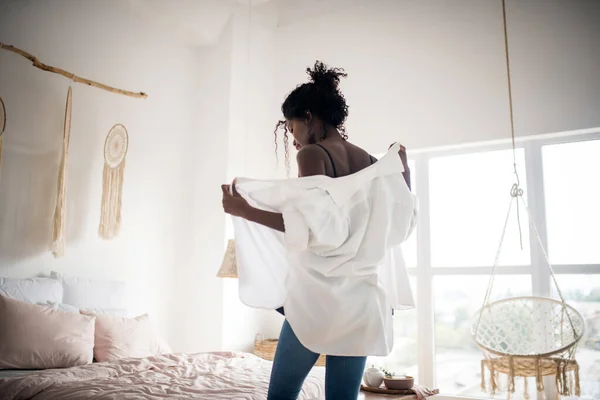 Темнокожая женщина надевает белую блузку утром — стоковое фото