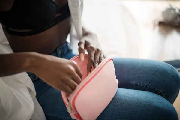 Крупный план женщины в джинсах с розовой косметической сумкой — стоковое фото