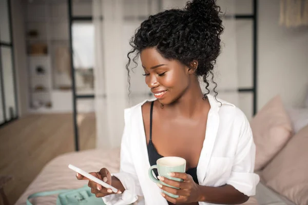Tilltalande kvinna ler medan du läser meddelande från pojkvän — Stockfoto